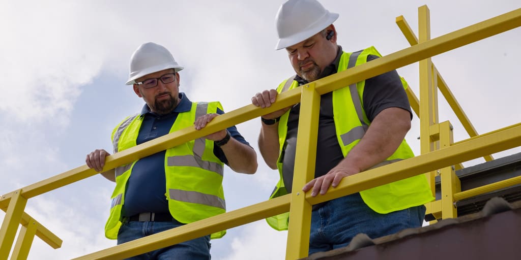 Two workers in safety equipment examining ReadySeries guarding system.