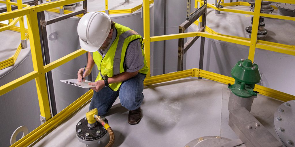 Man in hardhat and safety vest performing on-site evaluation.