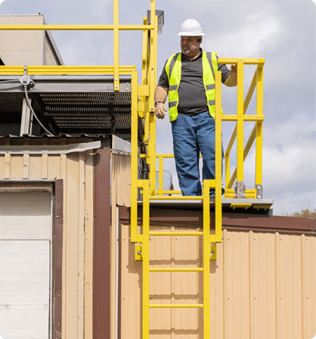 Man walking on a platform on his way to climb down a fixed ladder
