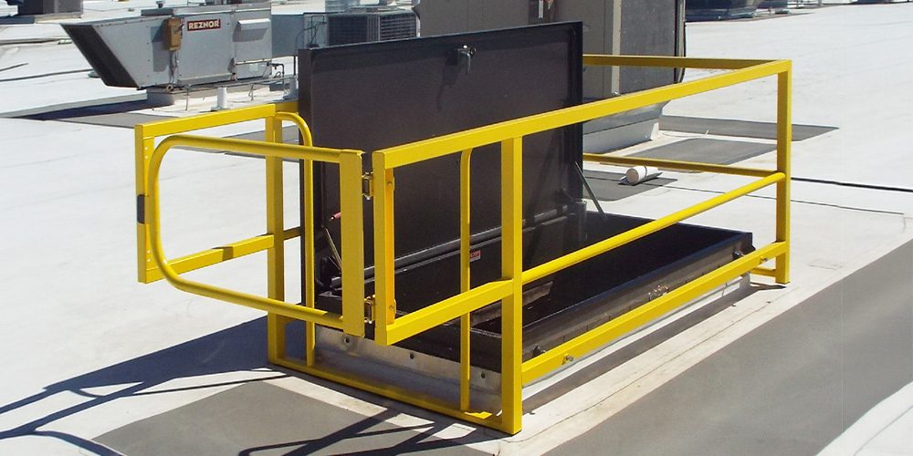 A rooftop hatch guard surrounded by yellow safety railing.